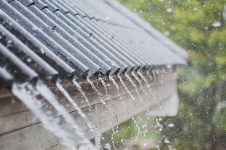 Rainwater flowing from a metal roof during heavy rain